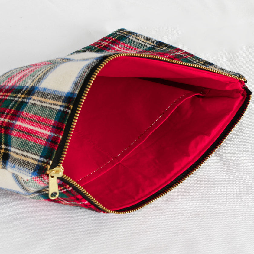 A red interior fabric and gold tone zipper on a red plaid large zip pouch 