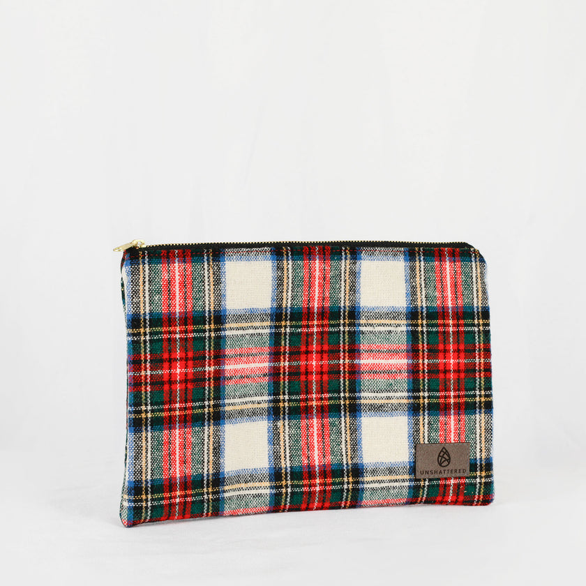 A large zip pouch with a red, green, and white plaid pattern and a small brand tag on the bottom right.