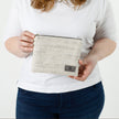 A woman holding a two-toned twill weave zip pouch wearing a white shirt with jeans  named after Sharon