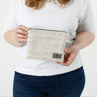 A woman holding a two-toned twill weave zip pouch wearing a white shirt with jeans  named after Sharon