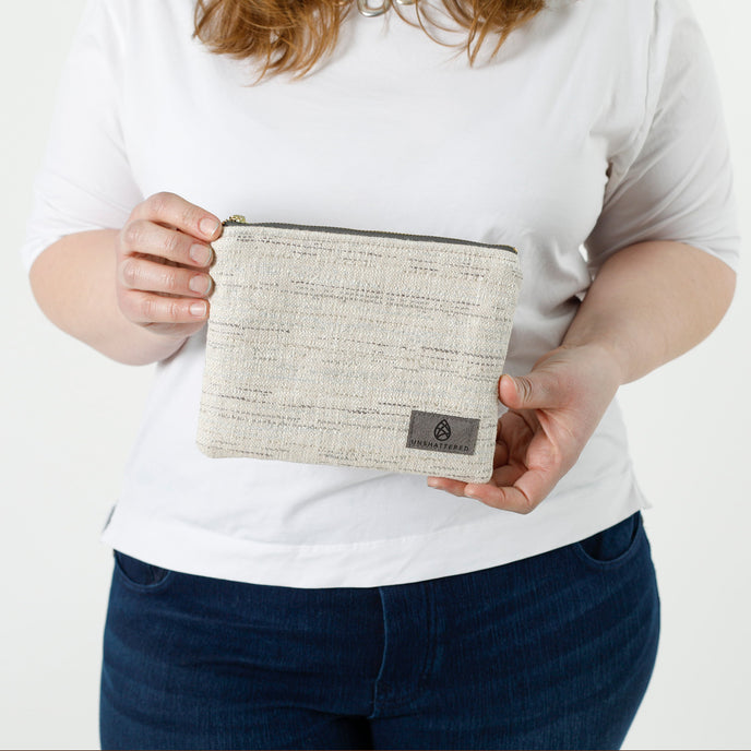 A woman holding a two-toned twill weave zip pouch wearing a white shirt with jeans  named after Sharon