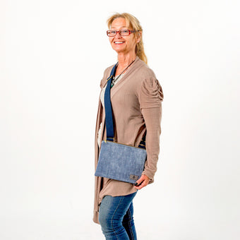 A woman wearing a blue crossbody bag smiling wearing glasses named after Shirley 