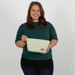 Woman holding a green and white patterned makeup bag against a plain background named after Sky