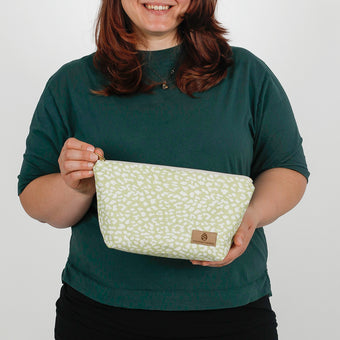 woman holding a green and white print makeup kit named after Sky 