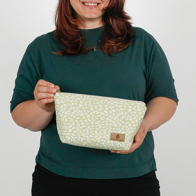 woman holding a green and white print makeup kit named after Sky 