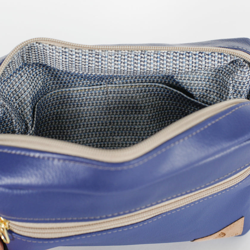 Blue toiletry bag with textured interior on a light gray background