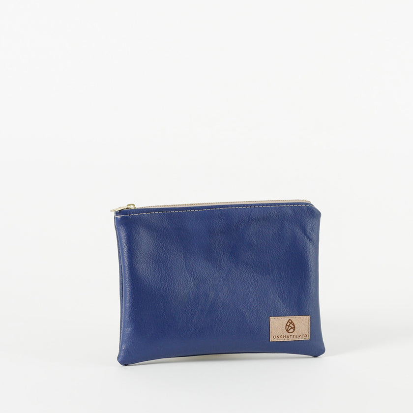 A royal blue zip pouch handcrafted from Southwest Airlines upcycled leather, with gold-tone hardware and a brand tag displaying Unshattered