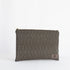 A light gray textured fabric zip pouch with brown polka-dot detailing and a brown leather brand tag on the bottom right corner.
