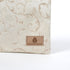 Tan suede label on a beige fabric zippered pouch with intricate patterns on a white background