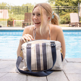 A woman in a swimming pool going into her gray and blue convertible handbag 
