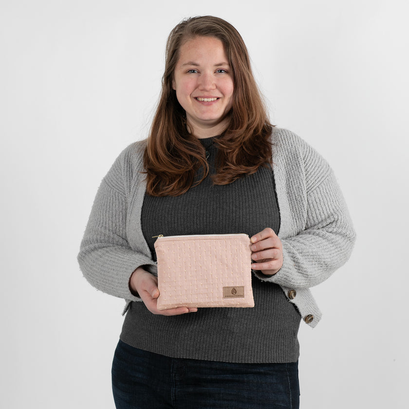 A woman holding a pink and yellow zip pouch named after Susan 