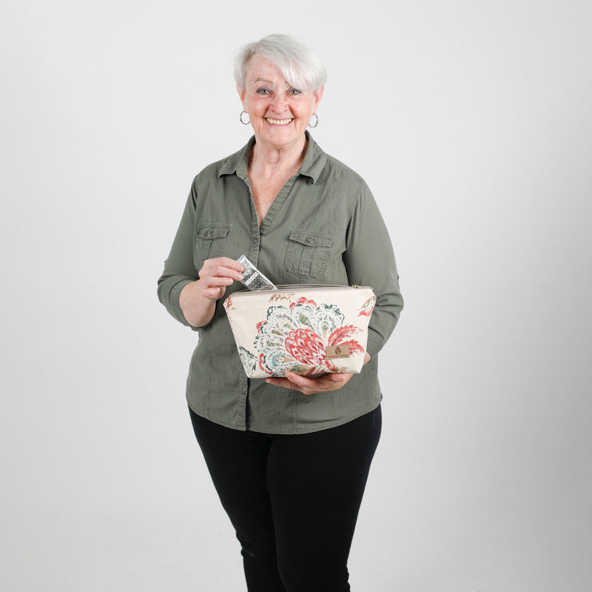Woman holding a floral-patterned makeup bag  against a plain background named after Tamir 