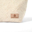 Tan suede Unshattered label on a beige textured upcycled fabric makeup bag on a white background
