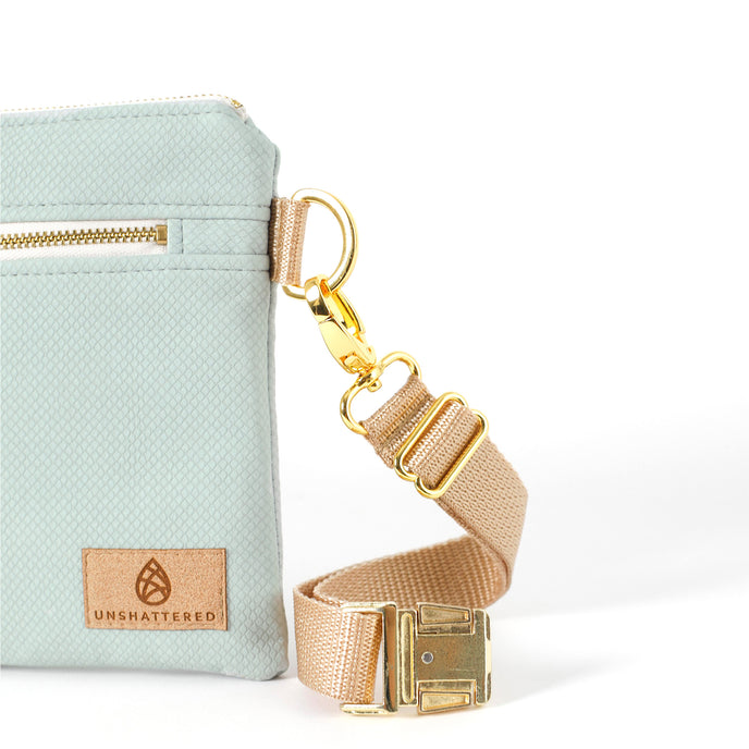 Tan suede label on a George 3-in-1 Bag handcrafted from light blue wipe-clean material with a beige belt bag strap and gold-tone buckle