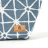 Tan suede Unshattered label on a blue geometric patterned makeup bag named Erin