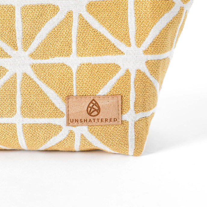 Tan suede Unshattered label on a yellow geometric patterned makeup bag named Isabel 