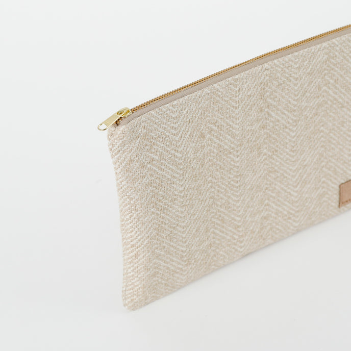 A gold tone zipper on a beige zip pouch 