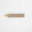 This beige fabric wristlet key clip features a playful dotted pattern and sleek gold-tone hardware.