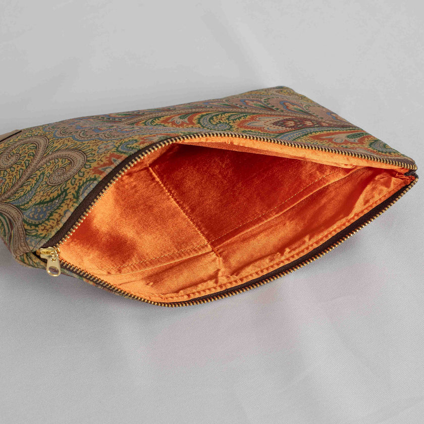 A orange fabric interior on this paisley large zip pouch with a gold tone zipper 