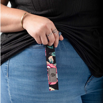 A black floral pattern loop keychain with a gray label and black hardware  