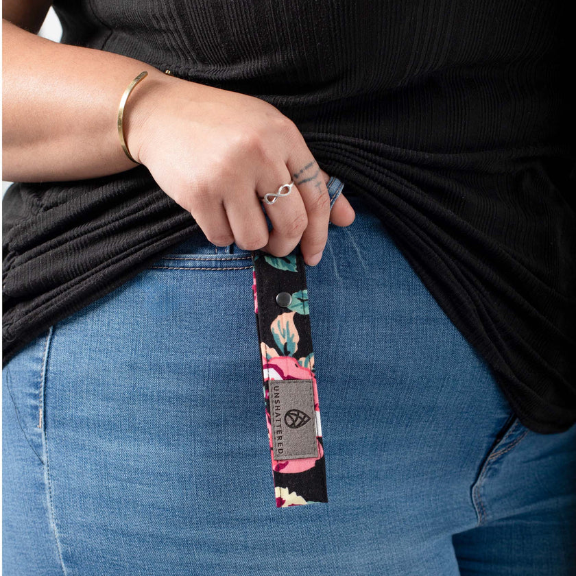 A black floral pattern loop keychain with a gray label and black hardware  