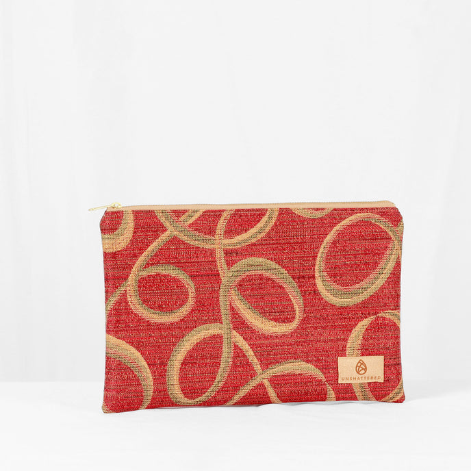 A red and gold zip pouch with a geometric pattern and a brand tag on the bottom right.