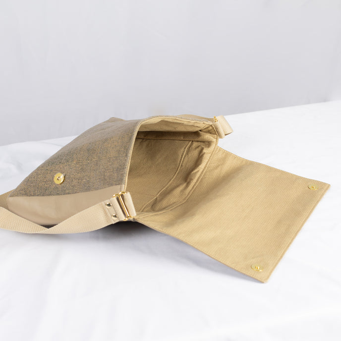 A beige fabric interior with a tan strap and gold hardware 
