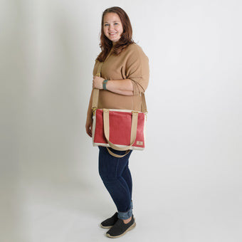 Woman holding a red and beige handbag against a plain background named after Tisha