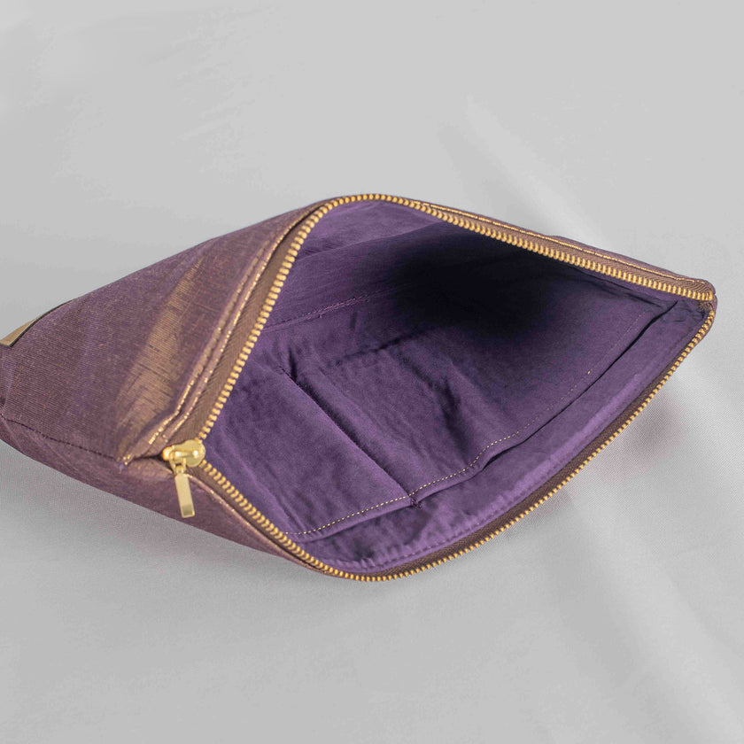 A purple fabric interior with a gold tone zipper on a gold and purple exterior large zip pouch 