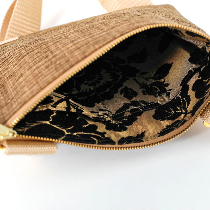 Close-up of a brown textured bag with a floral patterned interior on a white background named after Trisha 