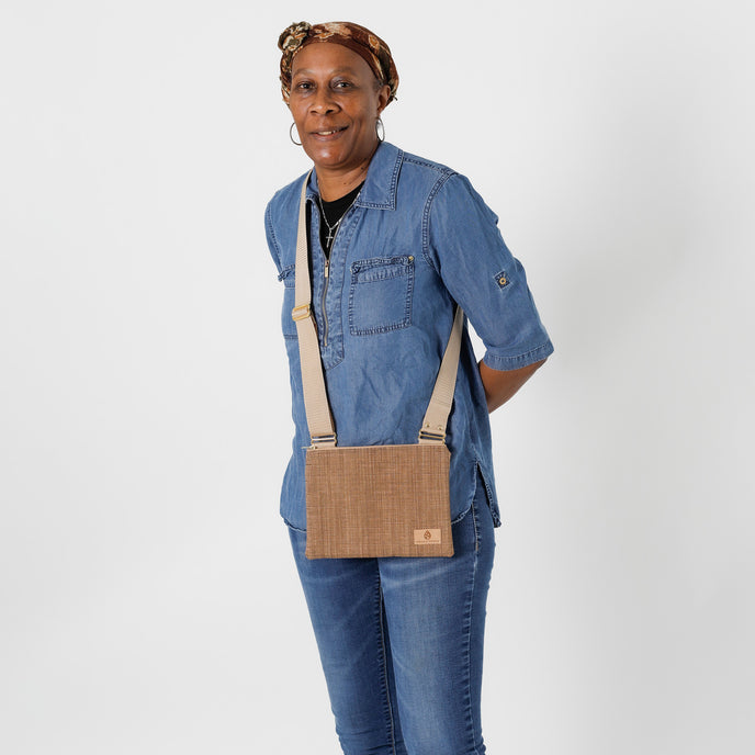 A woman wearing a brown textured crossbody pouch named after Trisha 