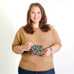 Woman holding a colorful patterned pouch against a white background