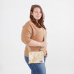 Woman holding a patterned crossbody bag against a plain background