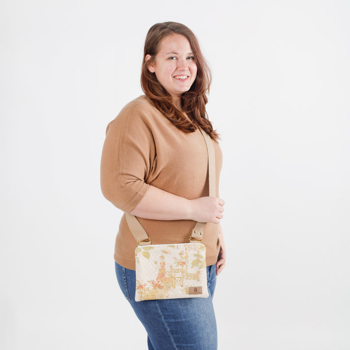 Woman holding a patterned crossbody bag against a plain background