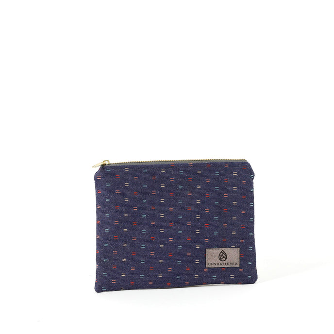 An upcycled blue fabric zip pouch named Nancy with a line rainbow pattern and gold-tone hardware on a white background