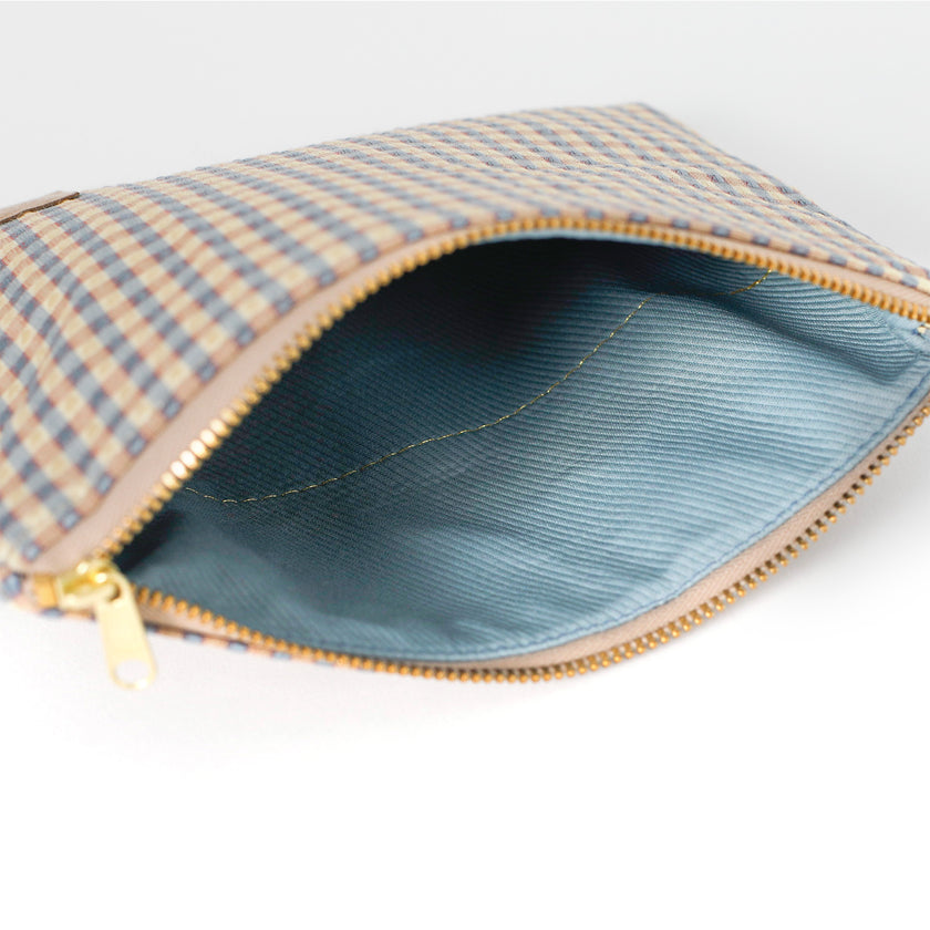 Open fabric pouch with upcycled checkered fabric exterior and solid blue interior on a white background