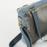 A gray strap with gold hardware on a charcoal luxury leather alternative with blue velvet accents 