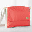 A red and white large messenger bag made from formula e racing material with an adjustable strap, shown with a focus on the front pocket and the brand's tag 