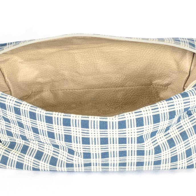 A tan luxury leather alternative material on the inside of the blue and white plaid exterior toiletry kit 