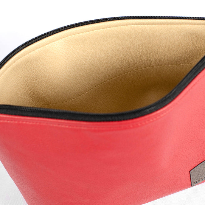 Beige wipe-clean interior of a red wipe-clean makeup bag handcrafted from upcycled materials by Unshattered