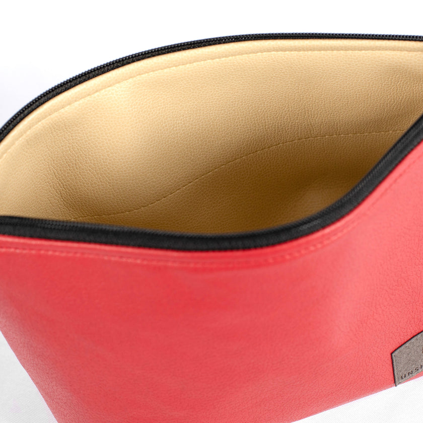 Beige wipe-clean interior of a red wipe-clean makeup bag handcrafted from upcycled materials by Unshattered