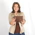 Woman holding a brown woven clutch against a white background