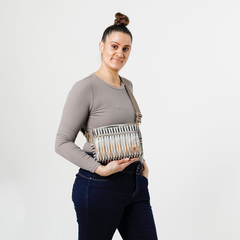 Woman holding a handcrafted errand bag made from upcycled vinyl in a brown chevron pattern with brown straps and gold tone hardware  named after Sally