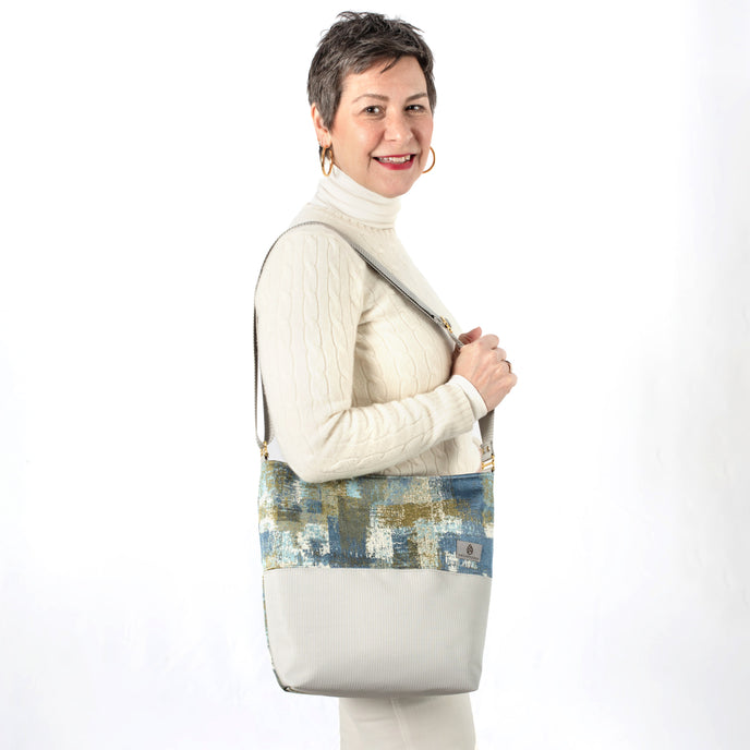 Woman holding a multi-color tote made from upcycled material paired with patio furniture material