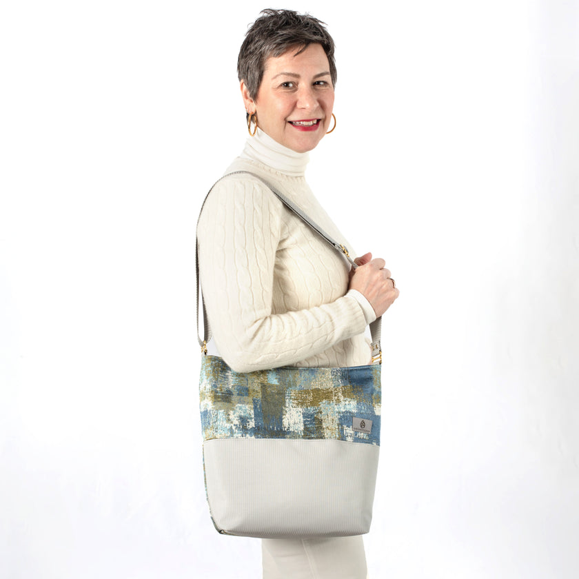 Woman holding a multi-color tote made from upcycled material paired with patio furniture material