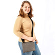 Woman holding a textured gray crossbody pouch on a white background