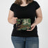 A woman holding a woodland camo zippered pouch with a brown label 