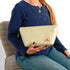 Woman holding a beige wipe-clean makeup bag, sitting on a patterned chair.