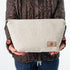 Woman holding a makeup bag named Theresa handcrafted from upcycled textured beige material