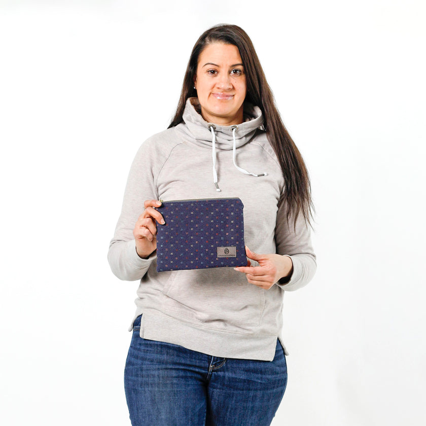 Woman holding upcycled blue fabric zip pouch named Nancy with a white background
